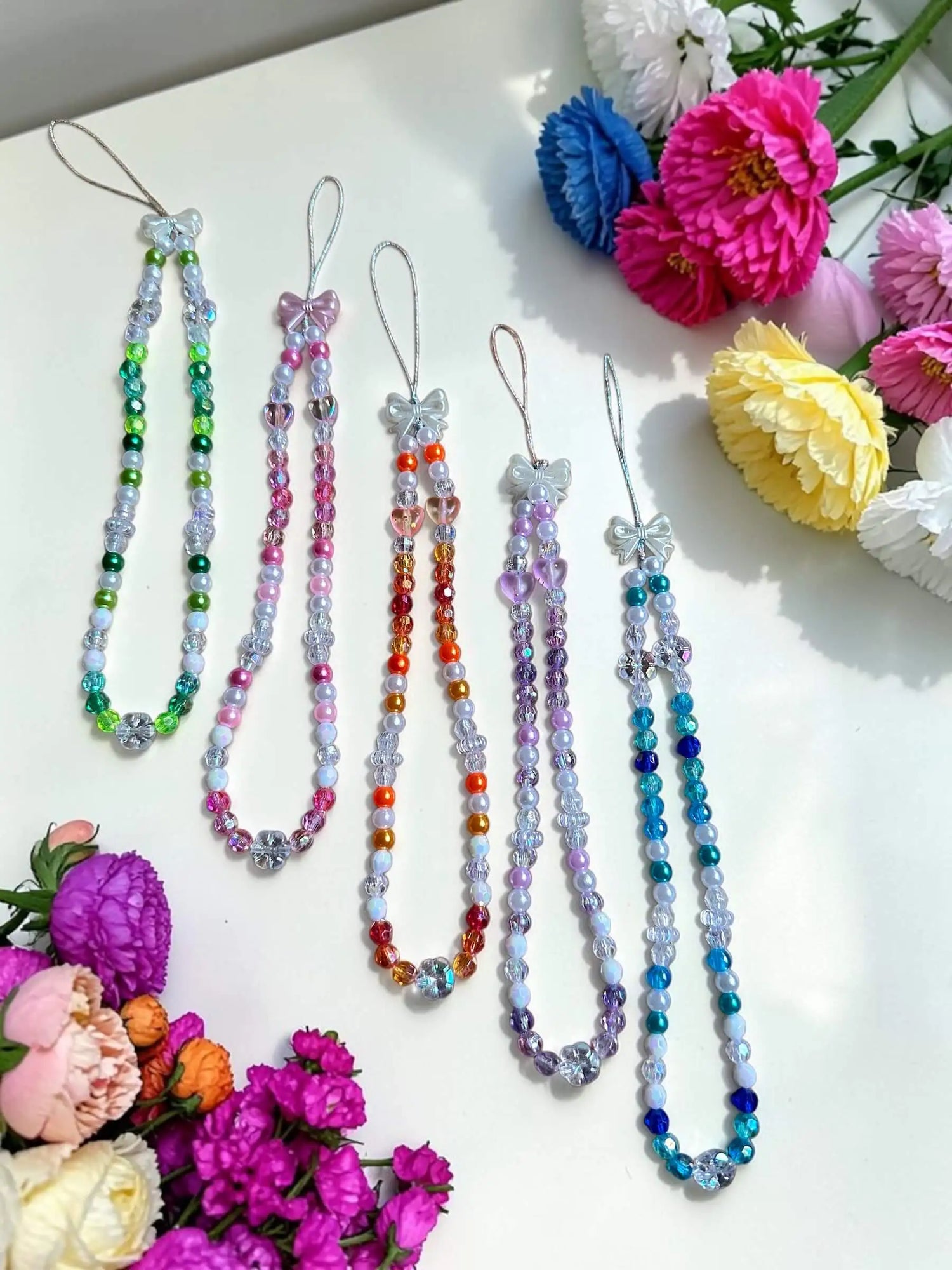 Collection of all five handmade beaded phone chains in different colorways by Enchanted Bookcase