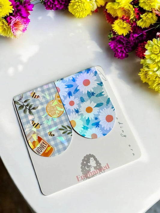 Honey Bee Picnic and Daisy Floral handmade holographic magnetic bookmarks displayed on Enchanted Bookcase branded card with flowers
