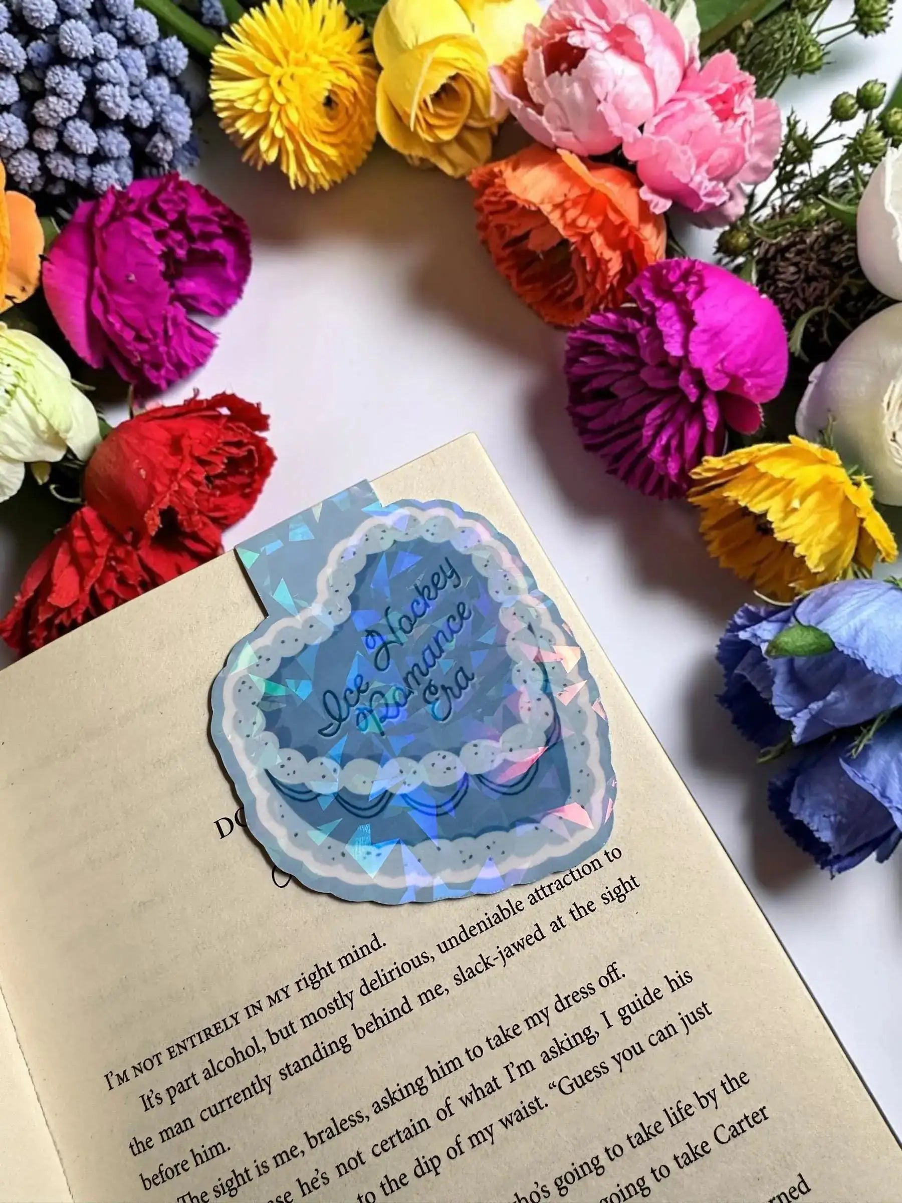 Ice Hockey Romance Era blue scalloped cake holographic magnetic bookmark holding the page in an open book by Enchanted Bookcase