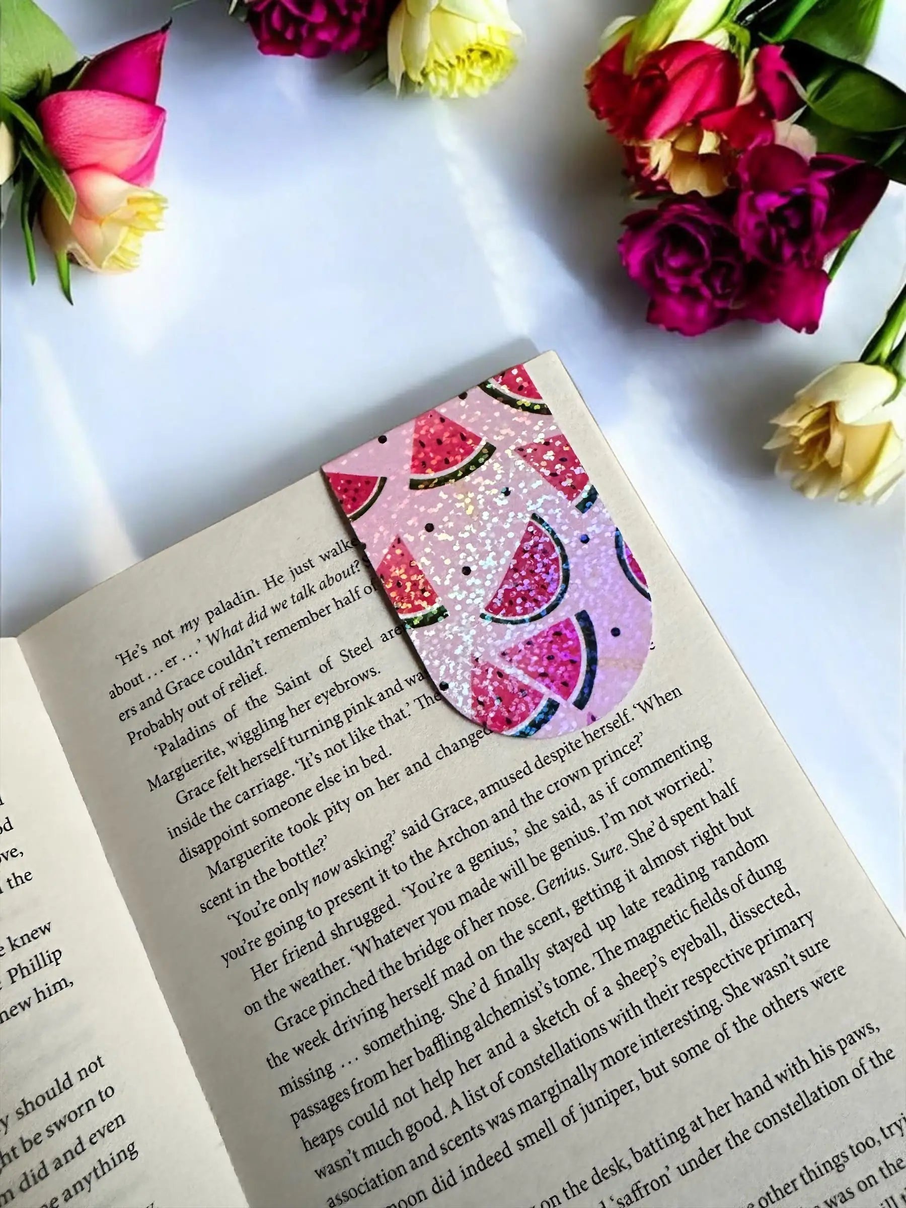 Sparkly glitter Watermelon magnetic bookmark placed in an open book by Enchanted Bookcase